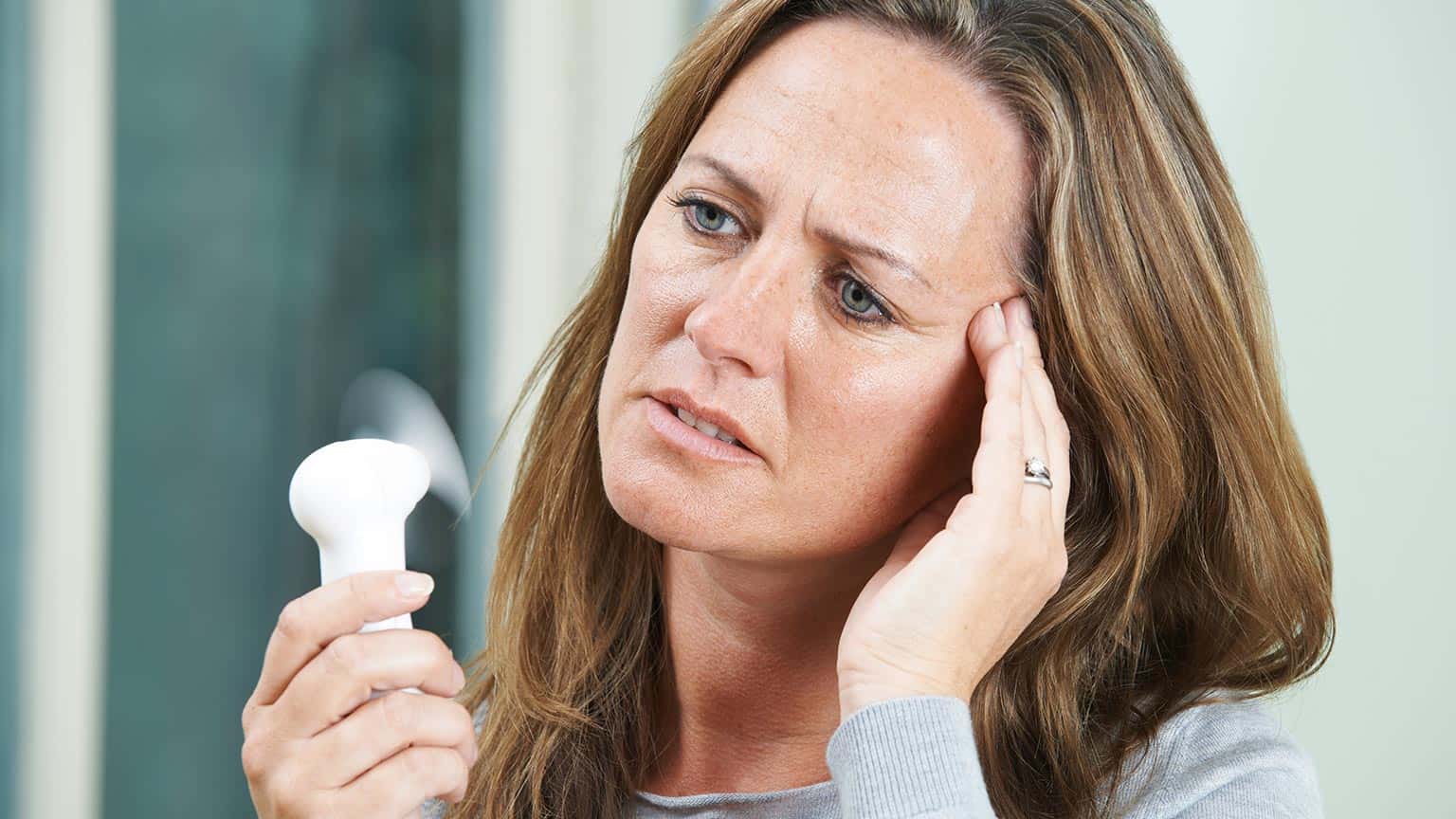 Mujer mayor sufriendo un sofoco - Artículo sobre sofocos durante la menopausia en Plenitud®. 